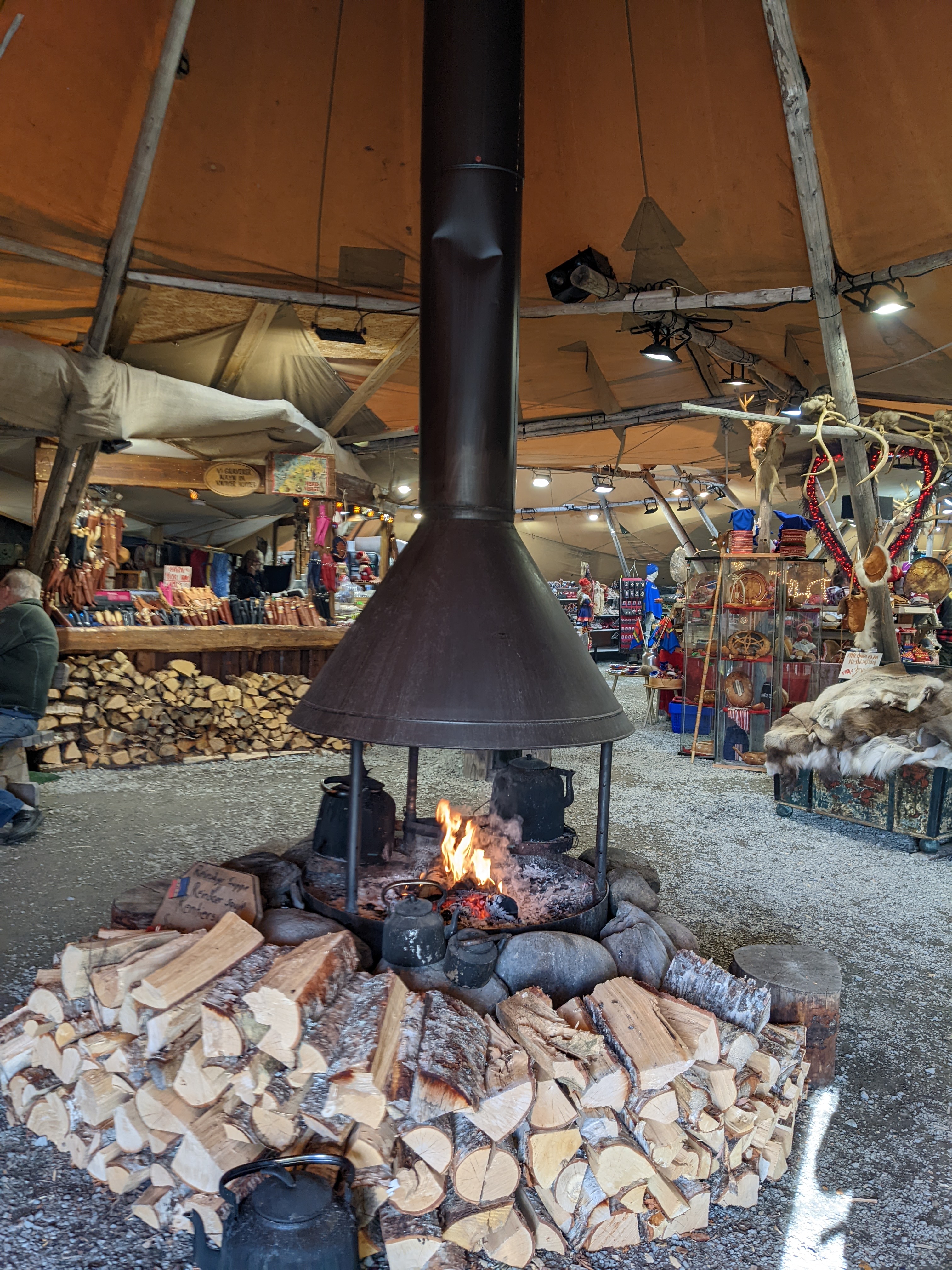 a stack of birch firewood in front of an open hearth. a stovepipe rises above the fire