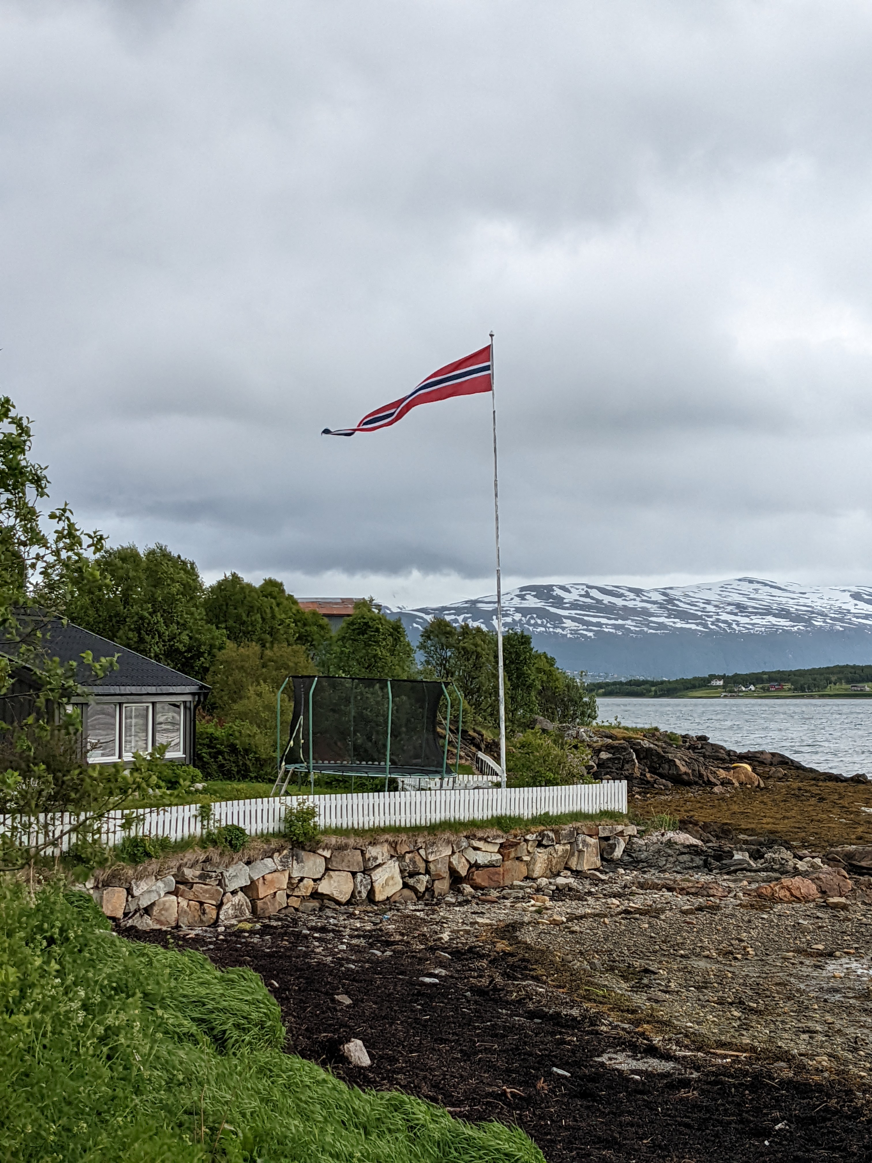 a home on a rocky beach with a trampoline and norwegian flag