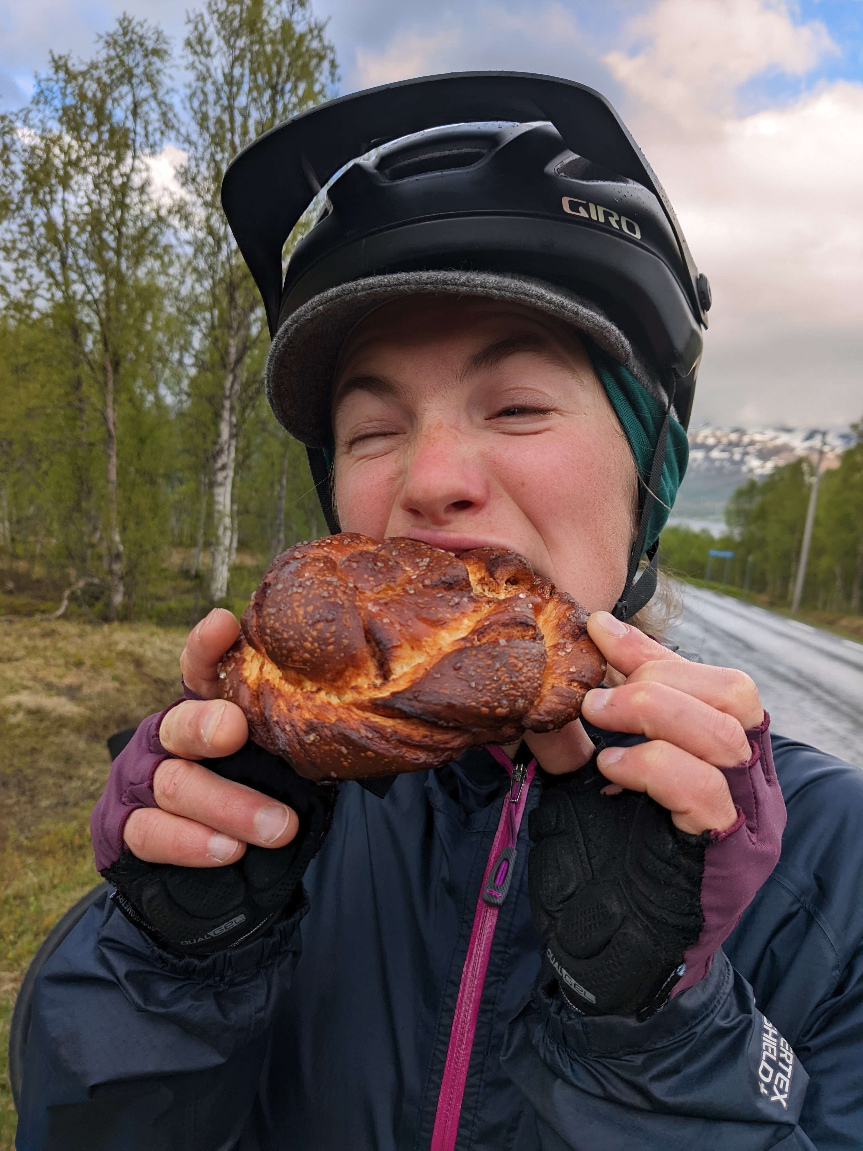 H biting into a huge, brown cinnamon-roll