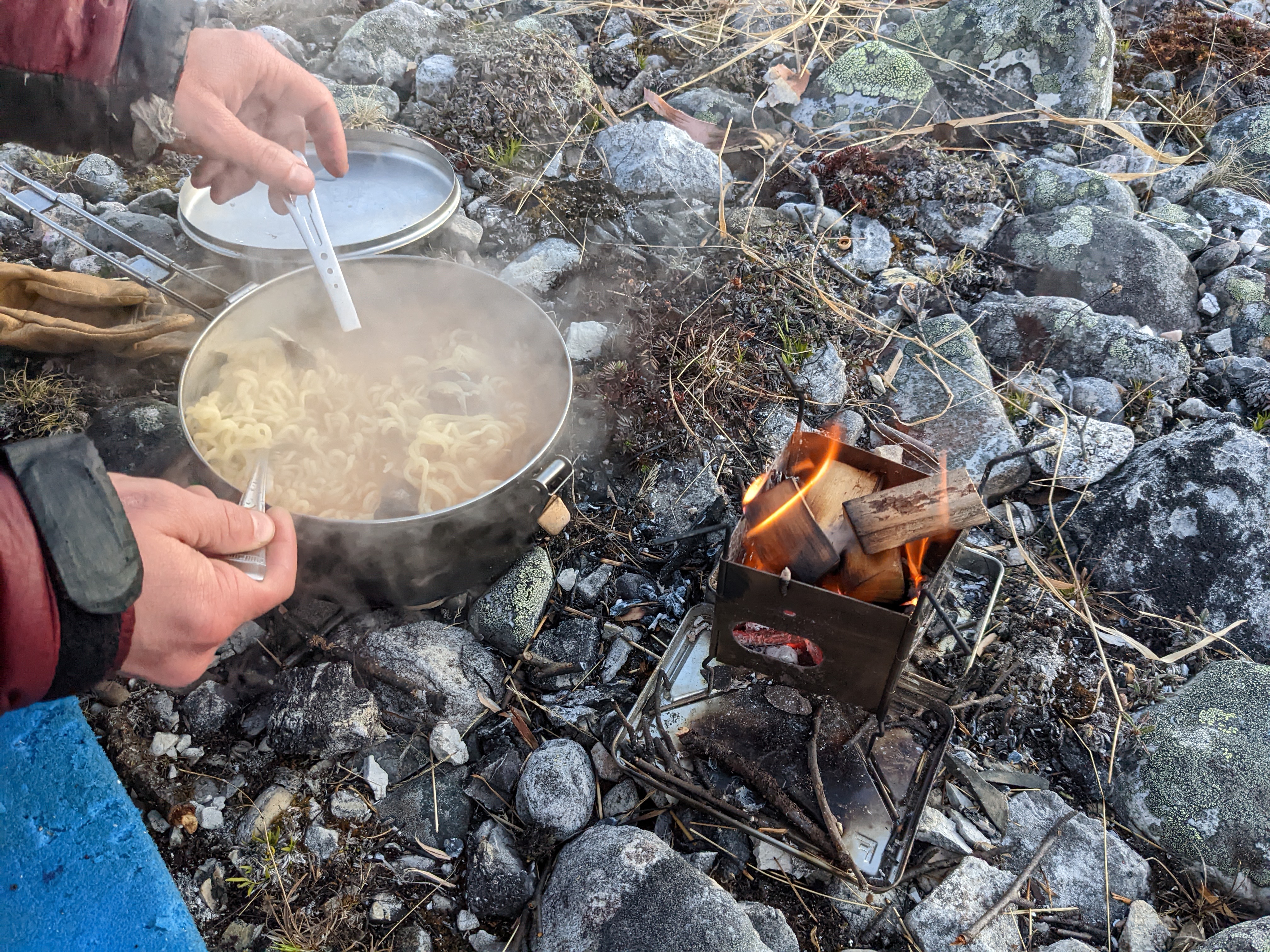 fancy ramen in a pot next to a burning firebox nano stove