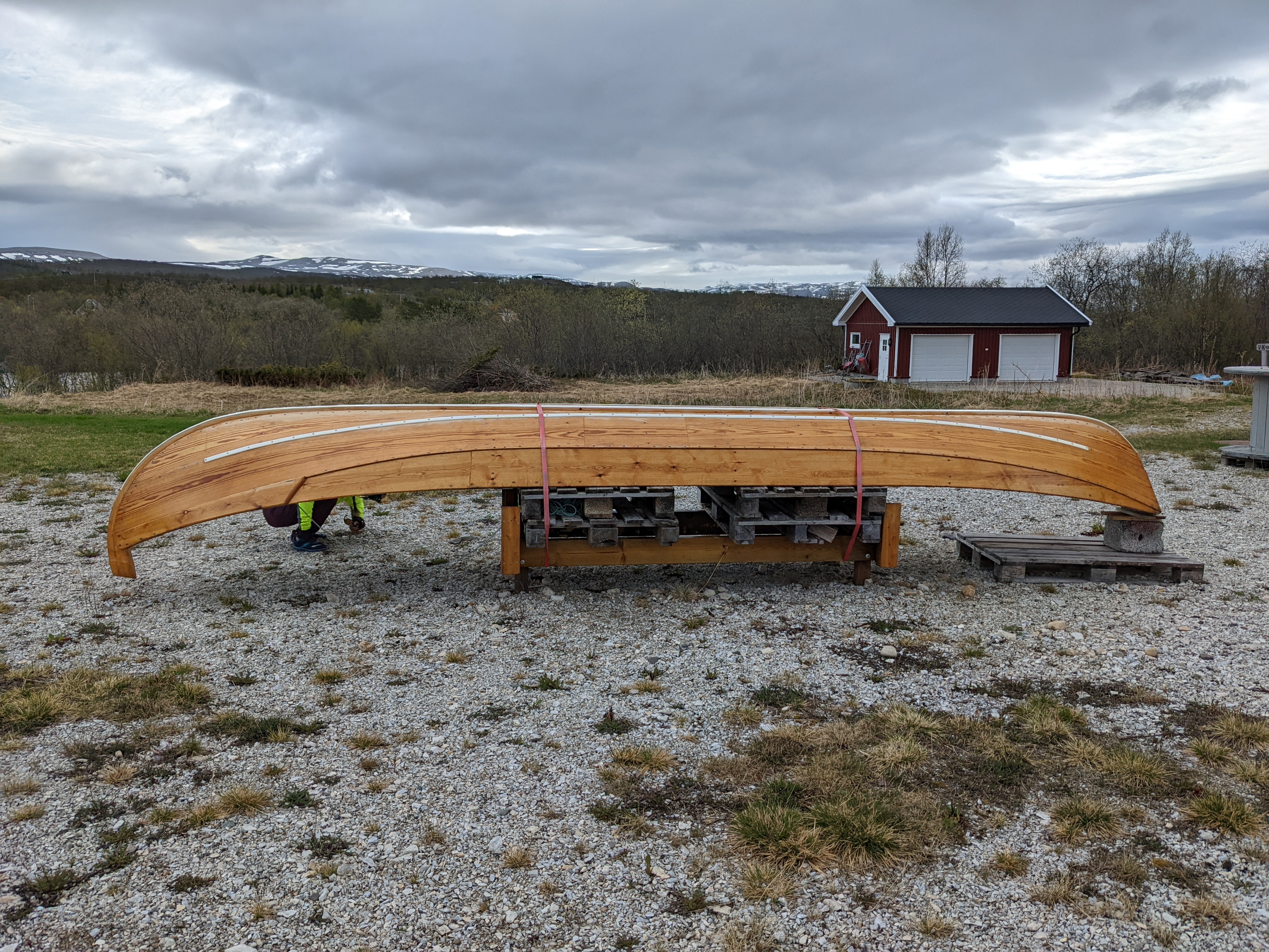 a traditional kven boat, upside-down on blocks. they are made of overlapped wood with metal fasteners