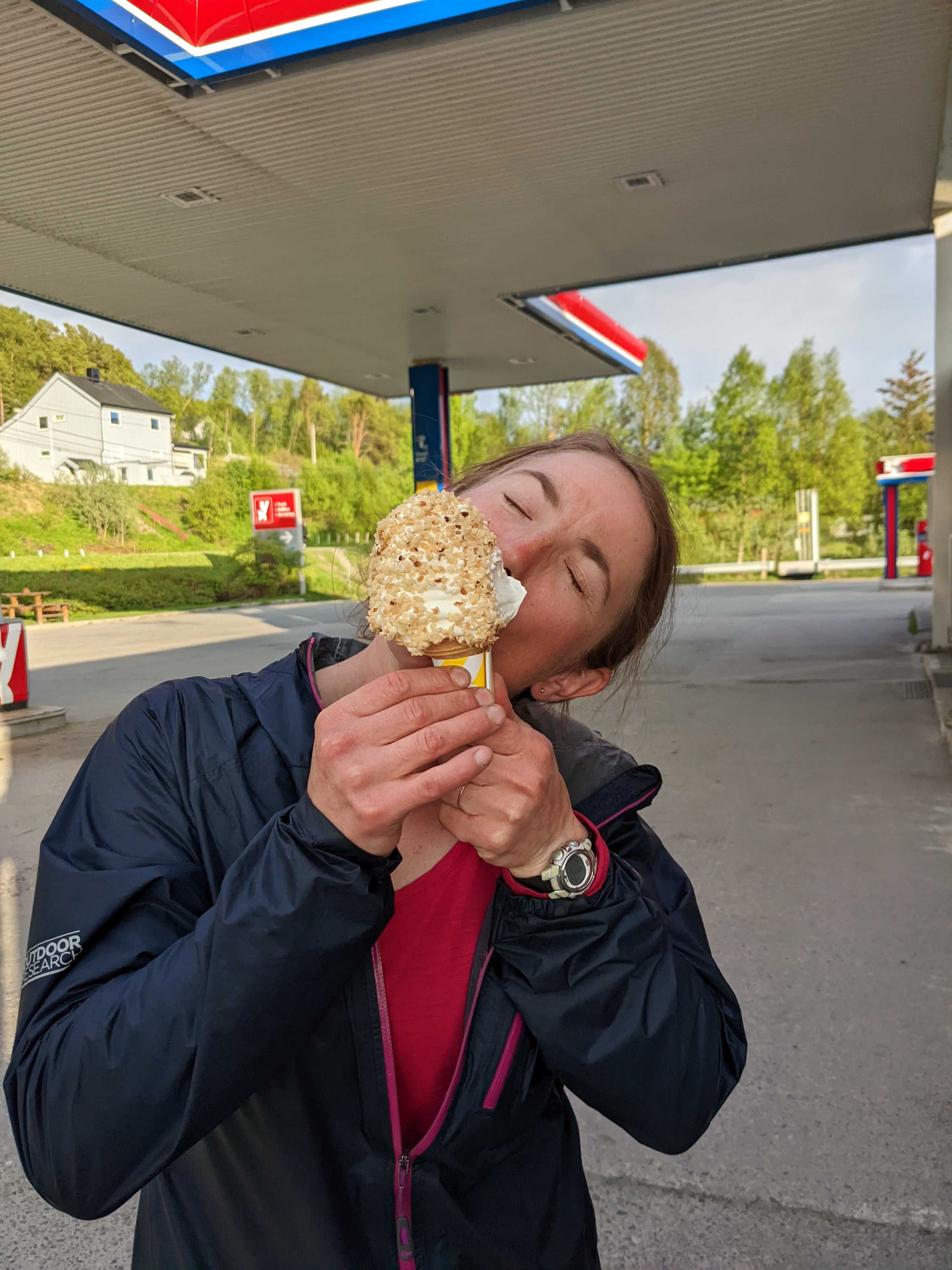 H biting a soft-serve ice cream covered in nuts