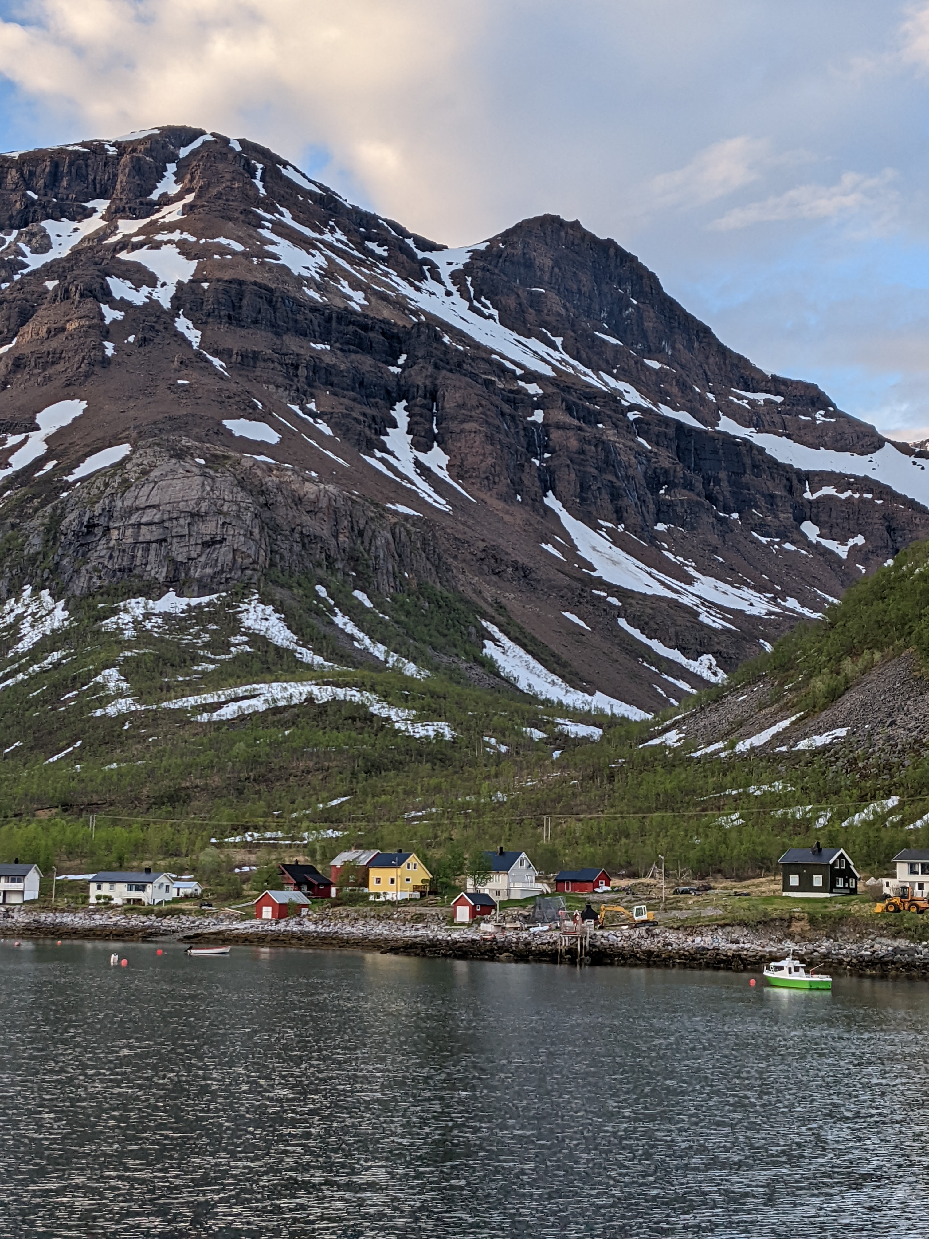 A few of the homes of Reinfjord, a small green boat, and a u-shaped hanging valley