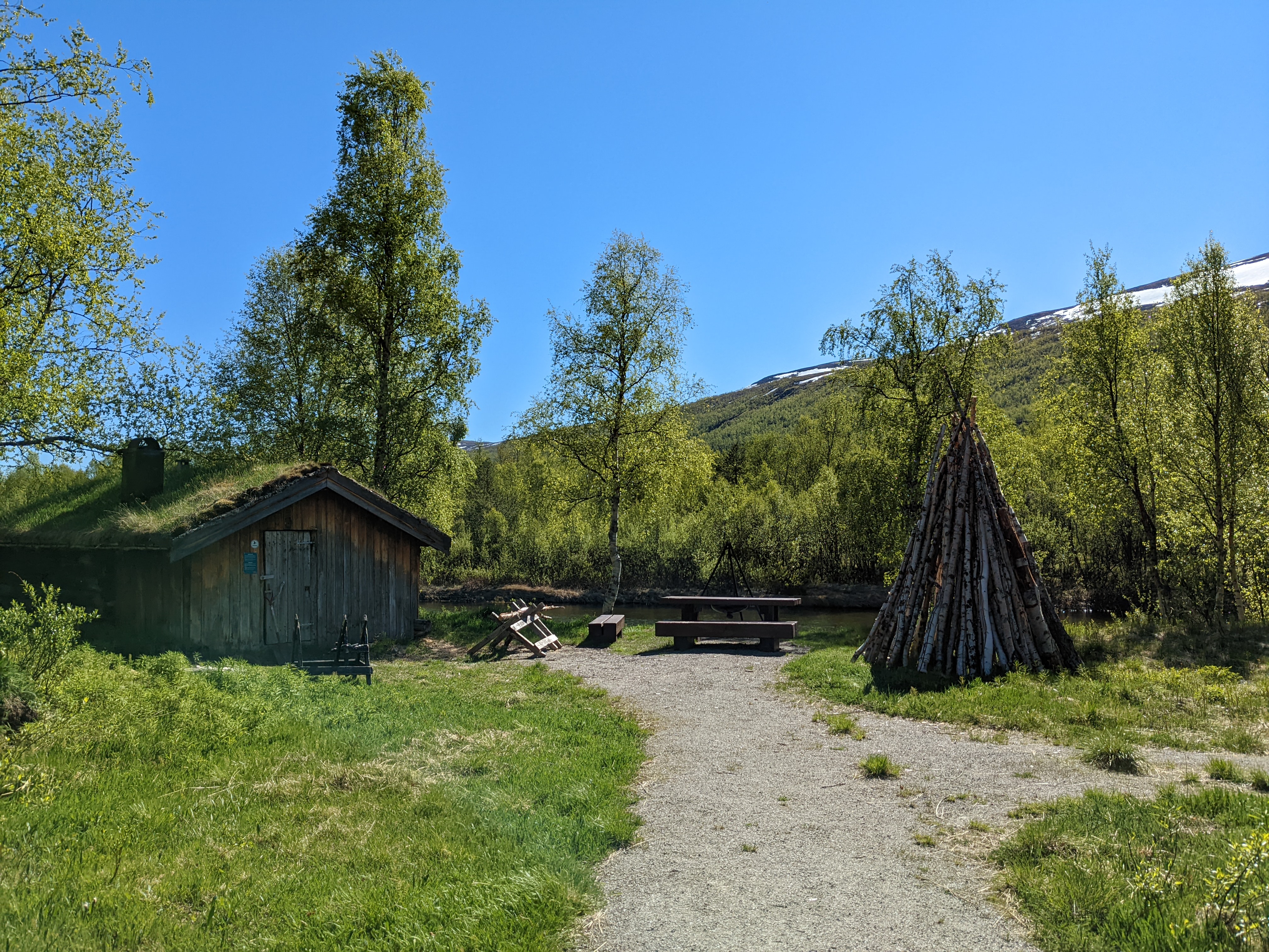 a gravel path leading to a wooden cabin with a turf roof