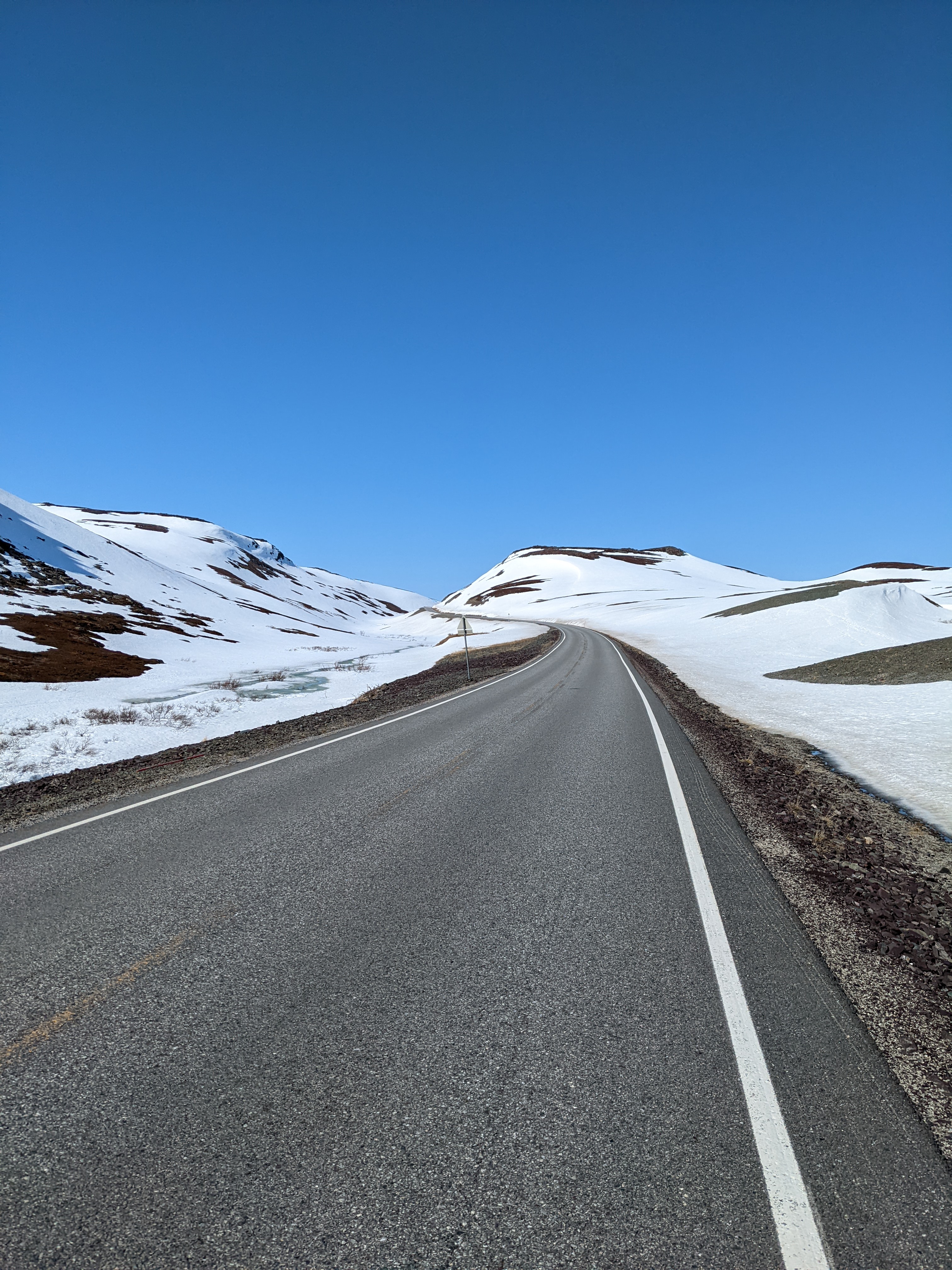 clear road through flat, snowy mountains