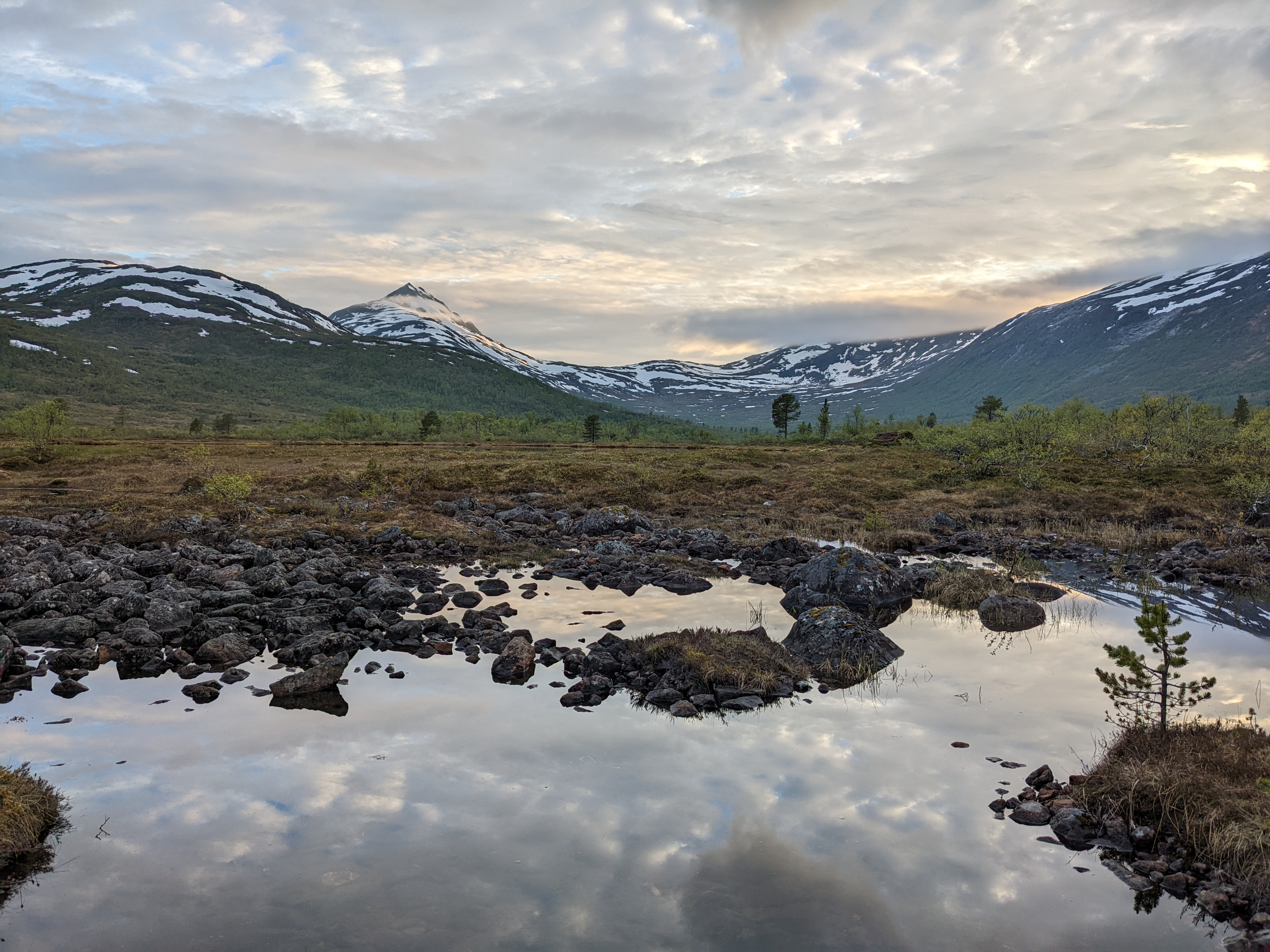 evening light over a rocky part of Åndervatnet reflecting clouds, with the Ånderdal peaks behind