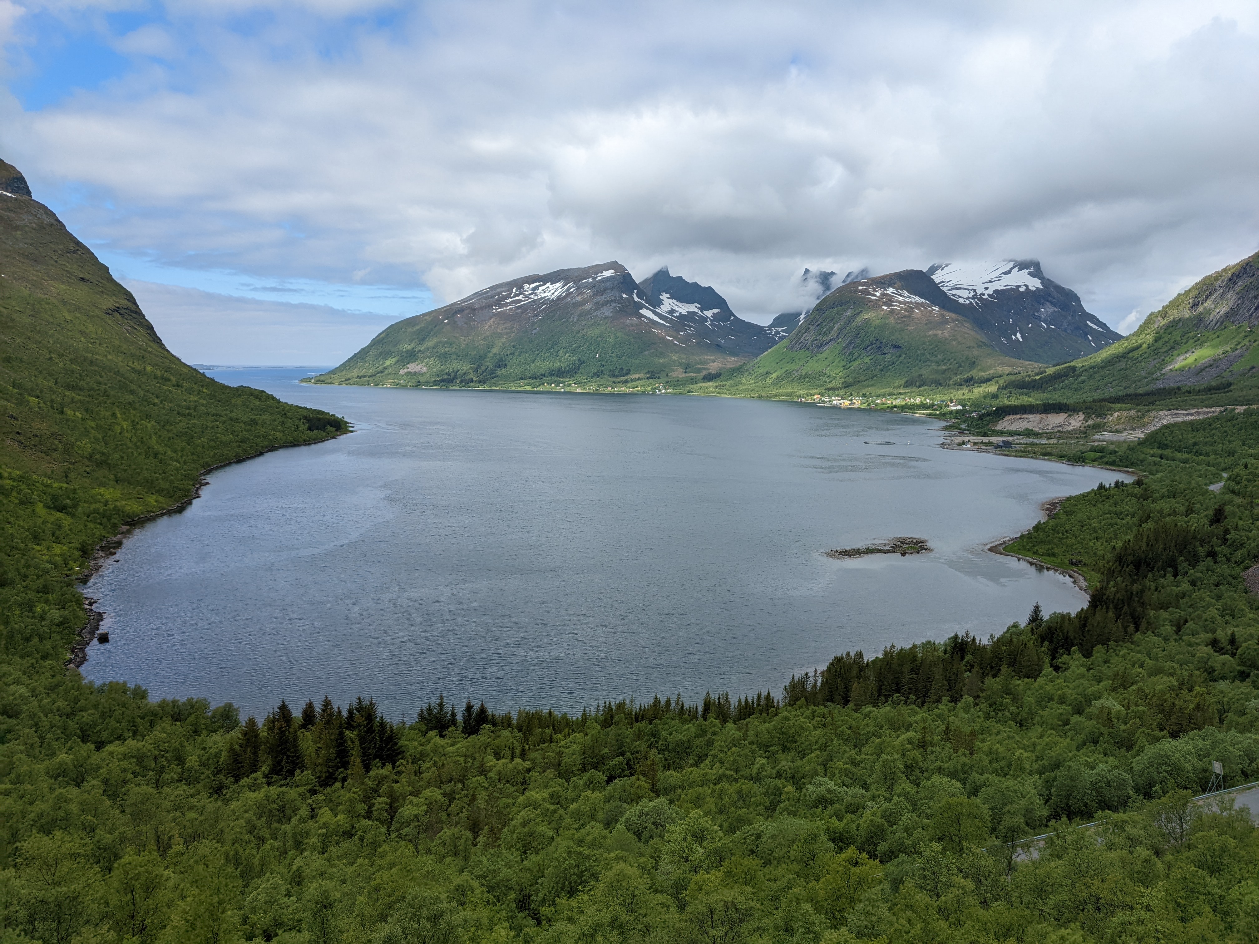 round, gree fjord shot from above the fjord bottom with a group of glacially carved peaks in the center across the water