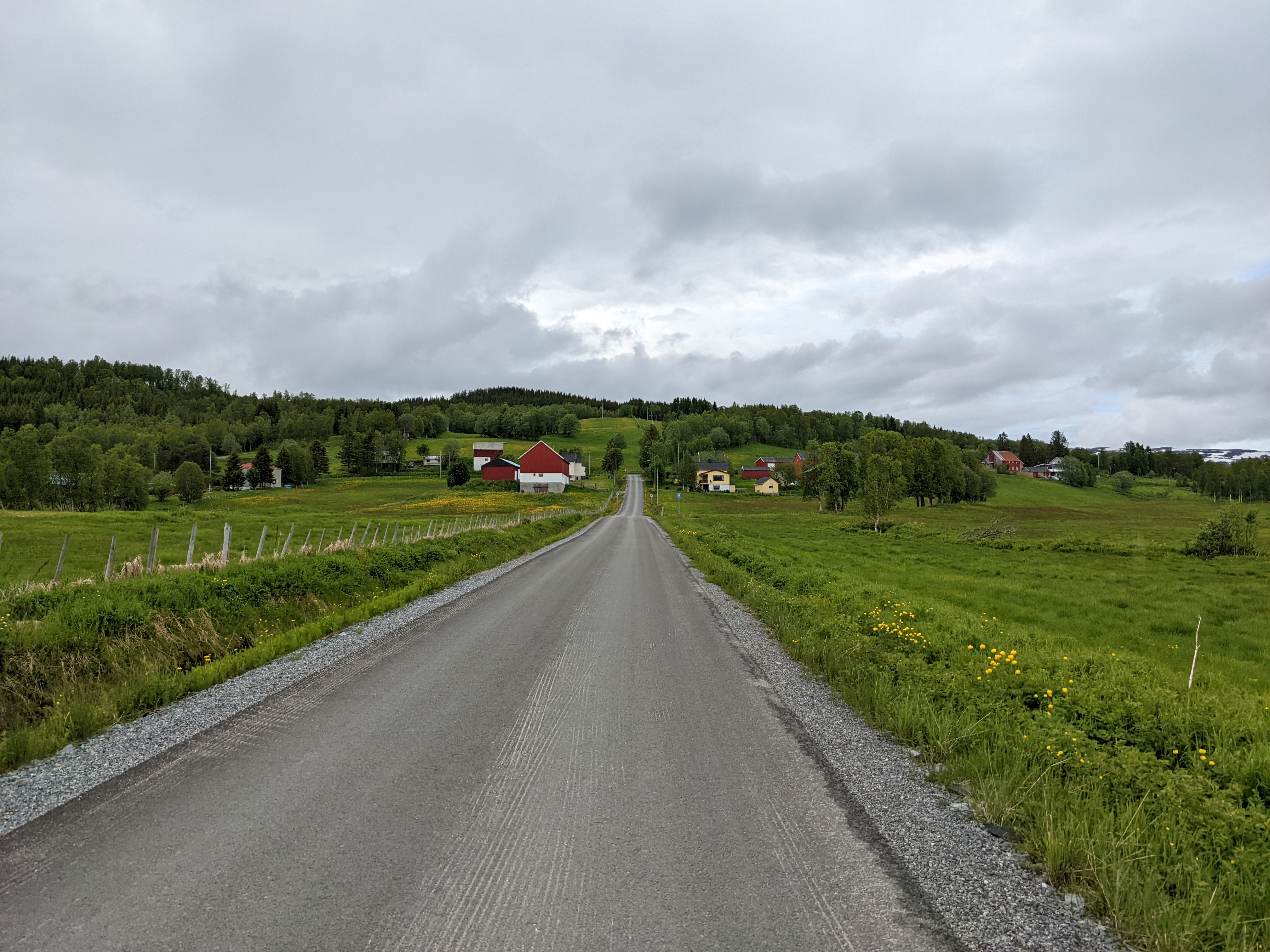 smooth paved roat sloping up toward an intersection with farms at the end and fields on either side