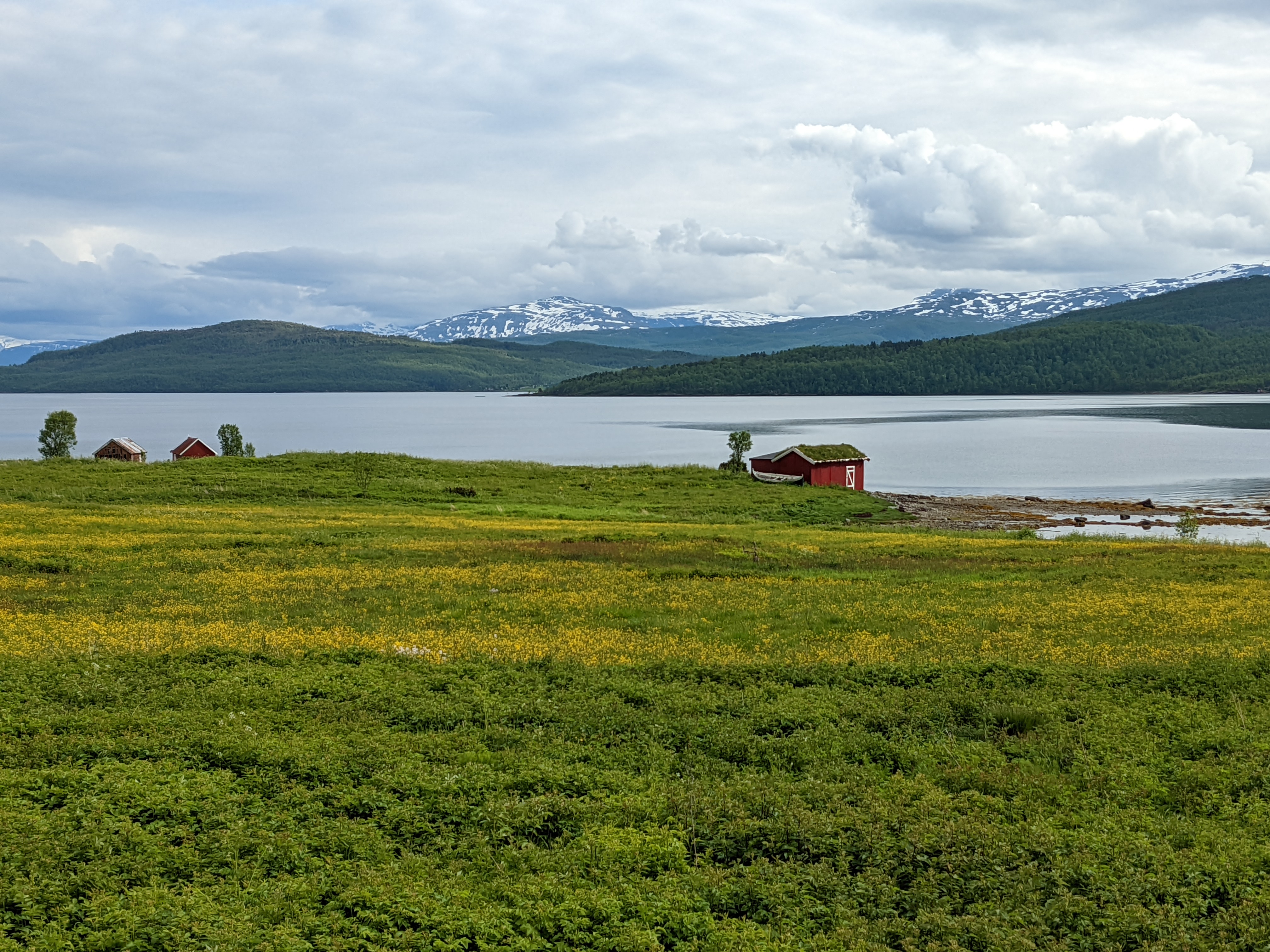 a small red boathouse on the edge of the fjord