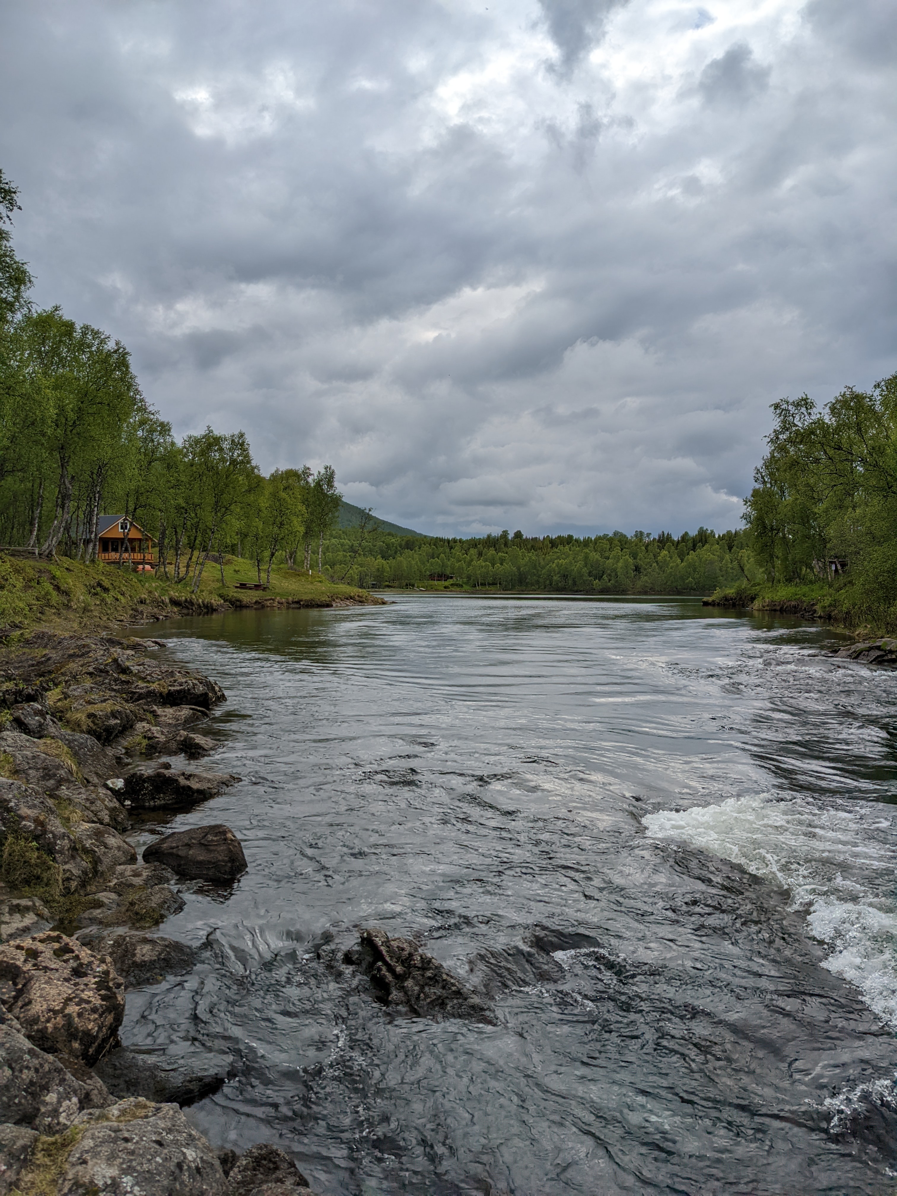 a view up a small river, with a mustard yellow cabin on the left bank