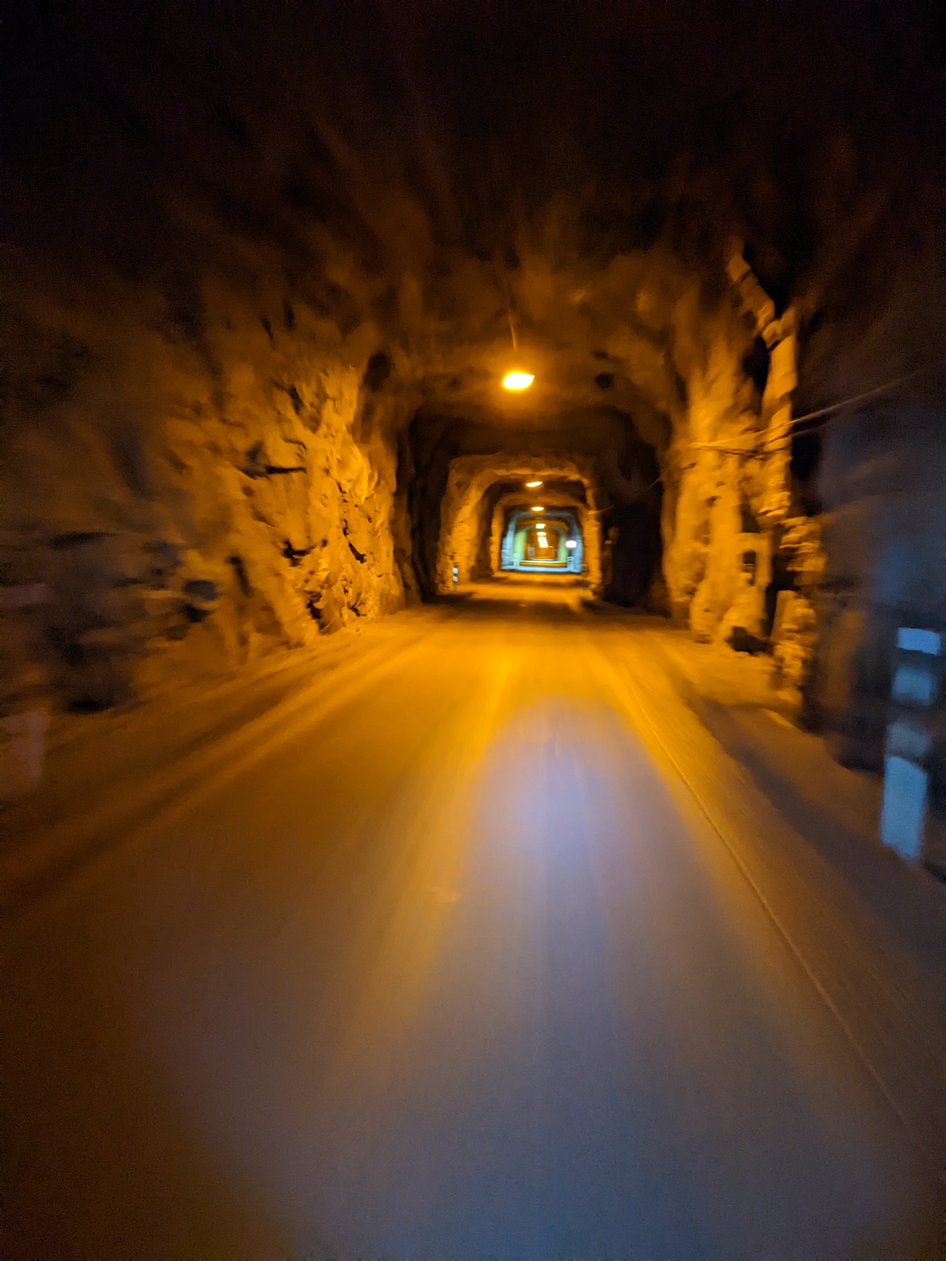 a blurry orange-hued photograph taken while riding through a stone tunnel