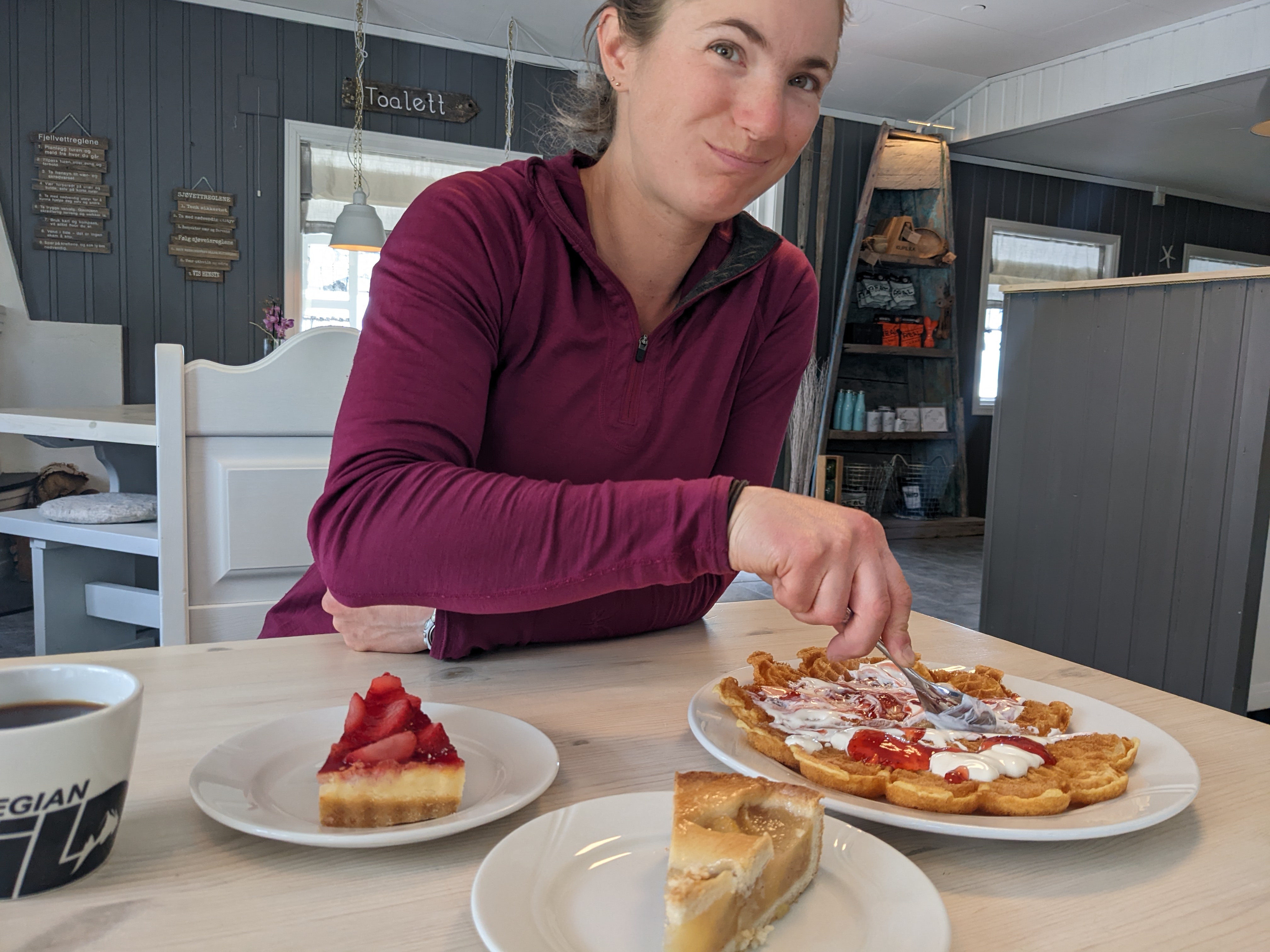 H with a goofy smile on her face, eating waffles and cakes