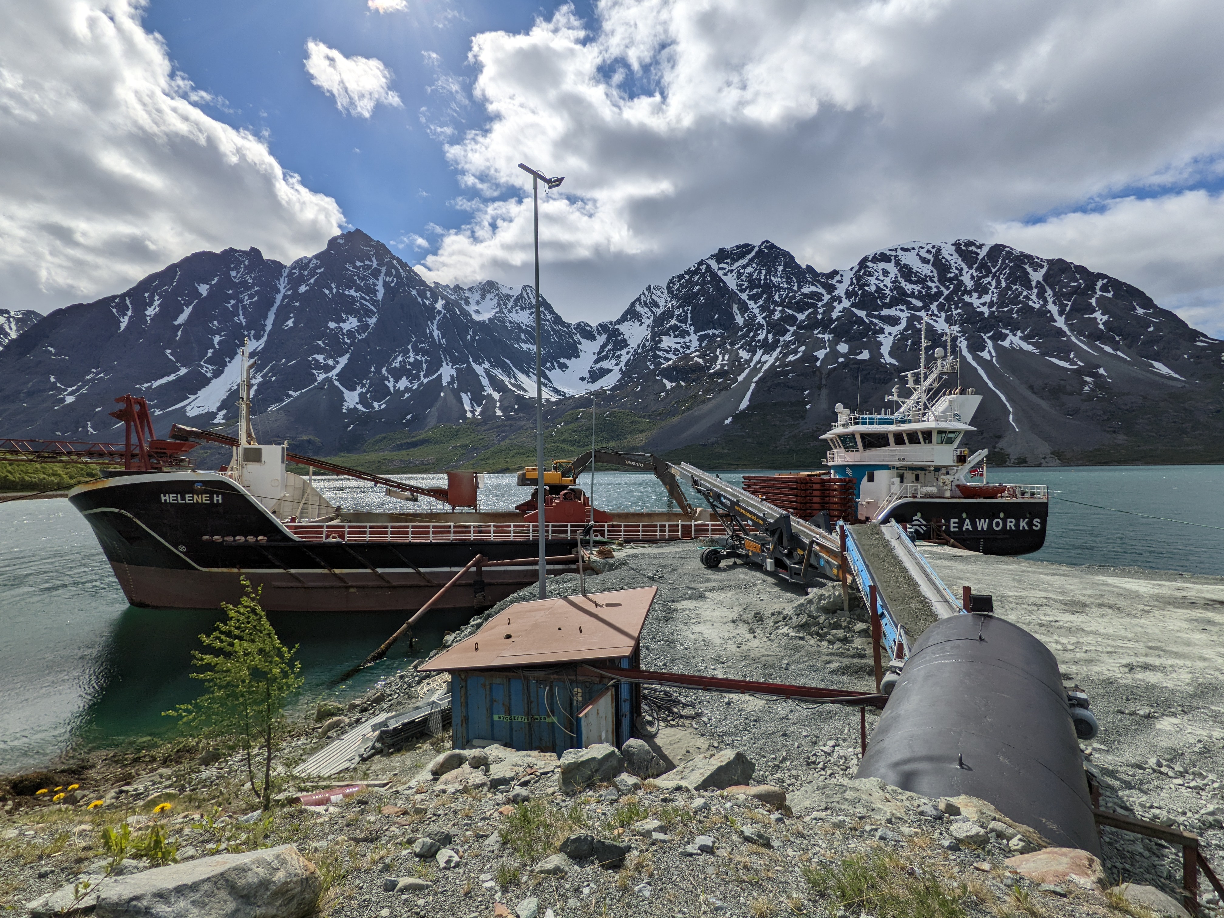 A gravel barge being filled in front of beautiful peaks