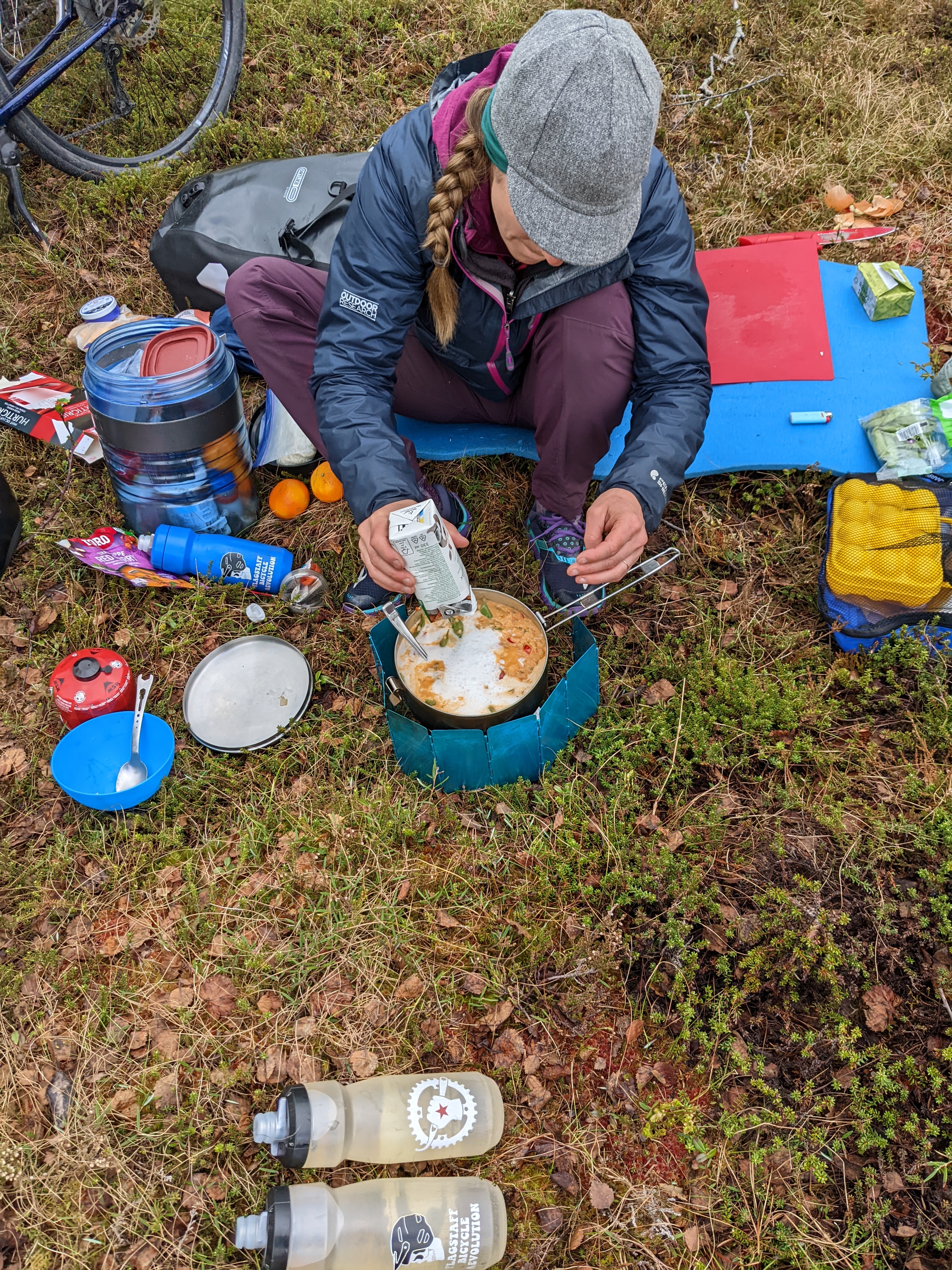 H pouring the coconut milk into the curry pot, with utensils and equipment all around