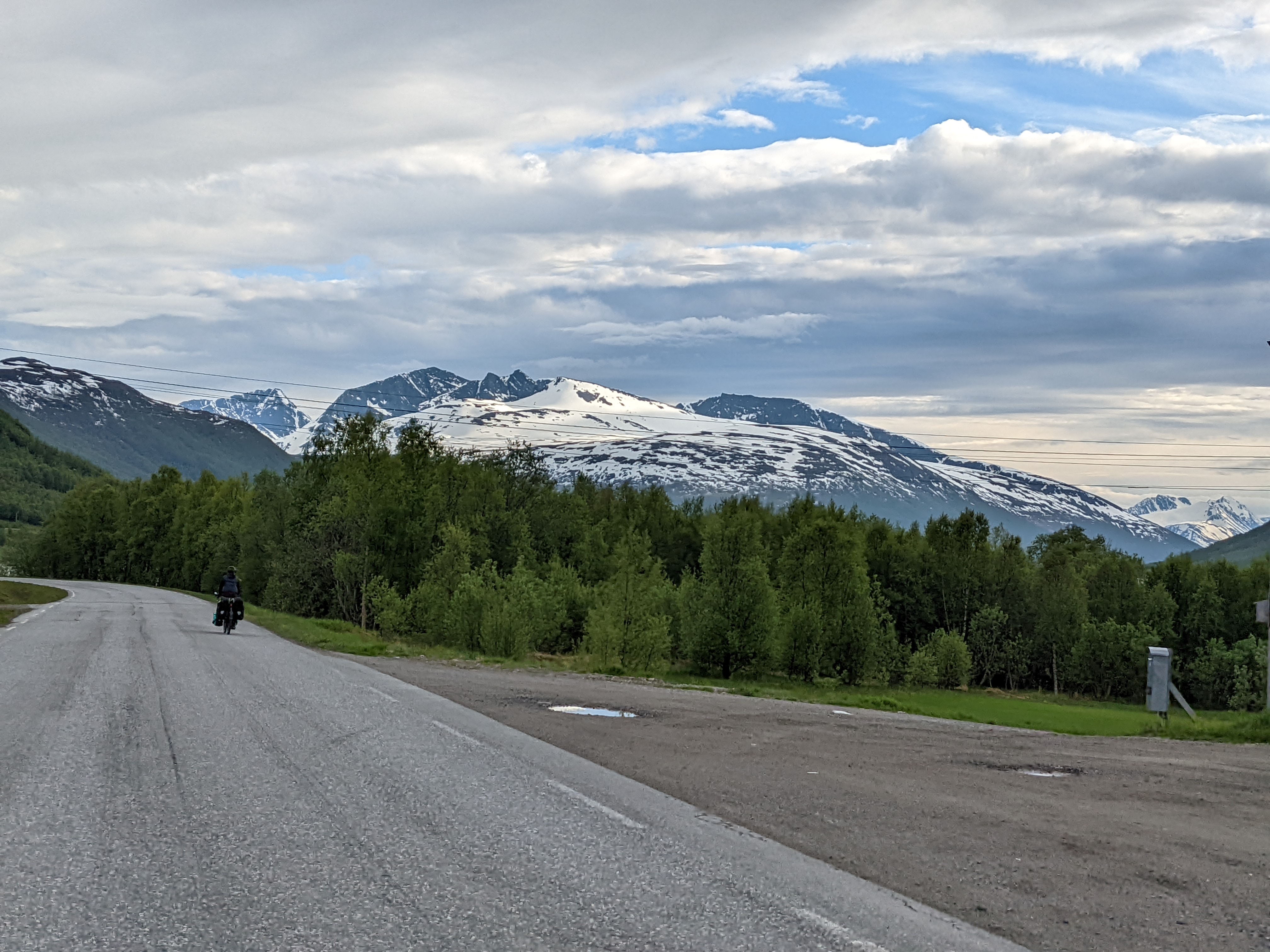 H riding past trees with a broad, skiable mountain view in the background